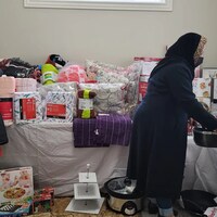 Deux femmes devant une pile de couvertures, d'appareils ménagers et de dons en tous genres.
