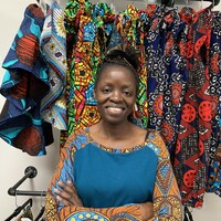 La  propriétaire de magasin d'habillement African Fashion and Accessories, debout bras croisés dans son magasin.