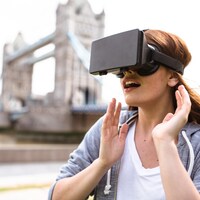 Une femme en train d'utiliser un masque de réalité virtuelle près du Tower Bridge de Londres.