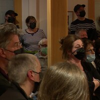 Des gens portant le masque sont entassés dans l'hôtel de ville de Percé le 3 mai 2022.