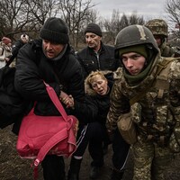 Des soldats et des civils viennent en aide à une femme.