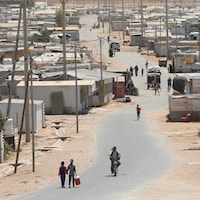 Des réfugiés syriens sur une route poussiéreuse. 