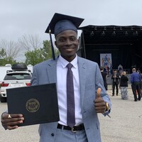 René Douvon, son diplôme à la main, sur le parc de stationnement devant l'Université Mount Royal.