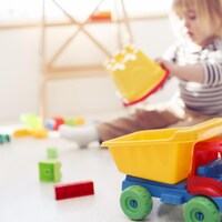 Un enfant joue avec des jouets, dont un camion de construction.