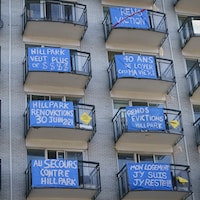 Des pancartes de protestation sont affichées sur les balcons des logements d'un immeuble.