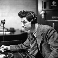 Dans un studio de radio, installé derrière une table tournante, le bruiteur Marcel Giguère.