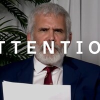 Robert Malone, un homme barbu en complet cravate, parle à la caméra en tenant une feuille. Le mot « attention » est superposé à l'image.