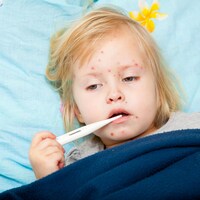 Une jeune fille au lit présente les symptômes de la rougeole.