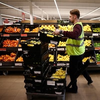 Un employé place des citrons dans les étals d'un supermarché.