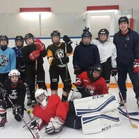 Un groupe de hockeyeuses en uniforme avec, à droite, Ryan Francis.