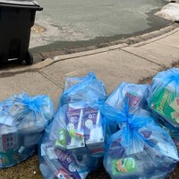 Des sacs bleus remplis de matières recyclables, sur un trottoir.