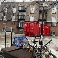 Un immeuble après un incendie, une benne et deux vélos.