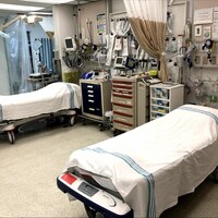 Deux lits entourés de matériel médical de soins intensifs dans une salle. 