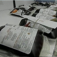 Échantillons sanguins ornés d'étiquettes de la Croix-Rouge et placés sur une table.