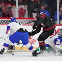 Connor Bedard, au milieu, en duel avec le gardien slovaque Adam Gajan, en quart de finale, lundi, au championnat du monde de hockey junior à Halifax.