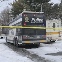Des véhicules de police dans une rue résidentielle, en hiver.
