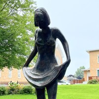 Sculpture d'une femme qui relève sa jupe.