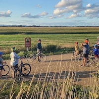 Un guide à vélo explique quelque chose à un groupe de gens à vélo lors d'une pause le long du chemin, sur un sentier.