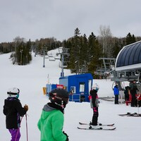 Quelques skieurs attendent au pied de la piste de ski afin de pouvoir utiliser le télésiège.