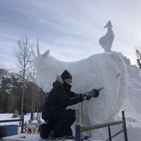 Un sculpteur travaille la neige pour donner l'apparence de fourrure à sa chèvre, fait de neige.