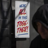 Une affiche de solidarité sur laquelle il est écrit en anglais « nous sommes tous ensemble dans cette situation » collée sur une vitrine d'un magasin torontois.