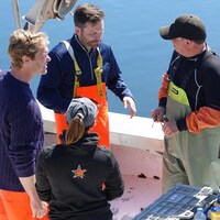 Alexis Deschênes et Paul St-Pierre Plamondon discutent avec des pêcheurs de homard.
