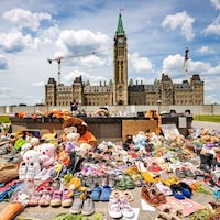 Des souliers d'enfants et des peluches près de la flamme du centenaire sur la colline du Parlement.