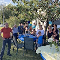 Des membres de deux familles réunies sur leur parterre avec des tables pour prendre un repas.