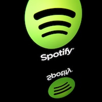 Le logo vert de Spotify reflète sur une vitre.