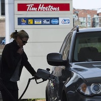 Une femme met de l'essence dans sa voiture à une station-service.