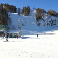Plan large sur une station de ski. On n'y aperçoit qu'une poignée de skieurs dans les télésièges et au bas d'une piste.