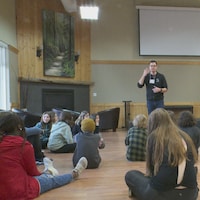 Steve Jodoin parle devant un groupe de jeunes assis.