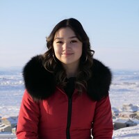 Tasiana Shirley se tient dehors devant une vue d'Iqaluit en hiver.