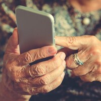 Les mains d'une femme âgée sur un téléphone cellulaire.