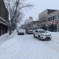 Des voitures circulent sur la rue Principale, enneigée.