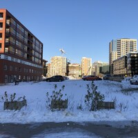 Un terrain vacant recouvert de neige, entre des immeubles.