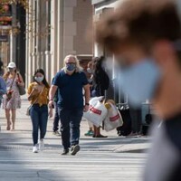 Des gens marchent dans la rue avec un masque.