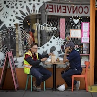 Deux personnes partagent un repas autour d'une table à l'extérieur d'un restaurant.