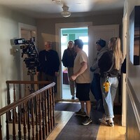 Une partie de l'équipe de tournage de la télésérie « Bon matin Chuck » dans un corridor d'une vieille maison.