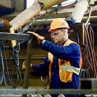 Un travailleur manipule un cadre en acier.