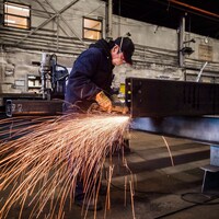 Un travailleur polit une pièce d'acier dans une aciérie de Colombie-Britannique.