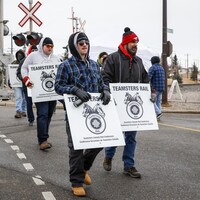 Des travailleurs marchent, pancarte dans leurs mains.