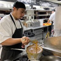 Un homme prépare un potage dans une cuisine de restaurant.