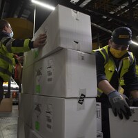 Des travailleurs déplacent des boîtes dans un entrepôt.