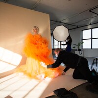 Le designer de mode Tristan Réhel replace la robe que porte Ingrid St-Pierre dans un studio de photo.