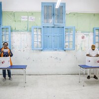 Un homme et une femme préparent leur bulletin de vote dans des isoloirs.