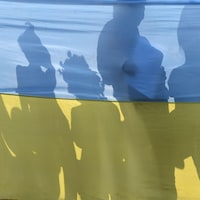 Des ombres de gens apparaissent sur un drapeau ukrainien. 
