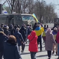 Quelques manifestants face à un camion militaire