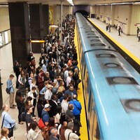Des usagers sur un quai du métro de Montréal, alors que le train arrive en station.