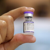 Une personne tient dans sa main  une bouteille du vaccin anti-COVID-19 Comirnaty de Pfizer-BioNTech.